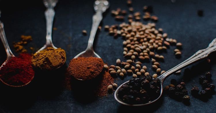 Einige Gewürze in Esslöffeln. Curry, Kurkuma, Paprika und Pfeffer